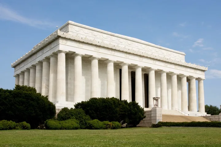 The Lincoln Memorial exterior with white marble columns against a blue sky.