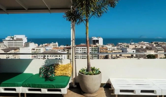 Rooftop terrace with pallet furniture and ocean city views, likely a hostel common area in Rio.