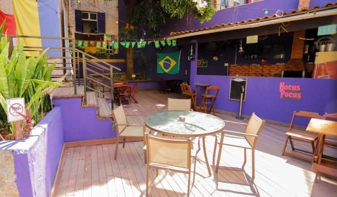 Colorful outdoor patio of a hostel called Hocus Pocus with Brazilian flag decor and bar area.