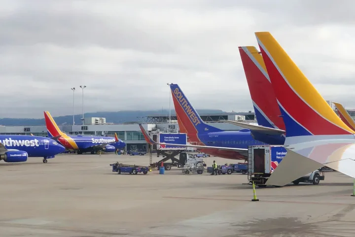 Multiple Southwest Airlines planes parked at terminal gates on an overcast day, tails visible in foreground.