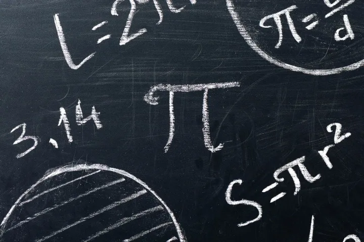 Chalkboard covered in pi symbol, 3.14, and mathematical formulas related to circles.