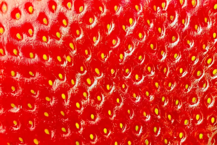 Extreme close-up macro shot of a bright red strawberry surface showing seeds and texture.