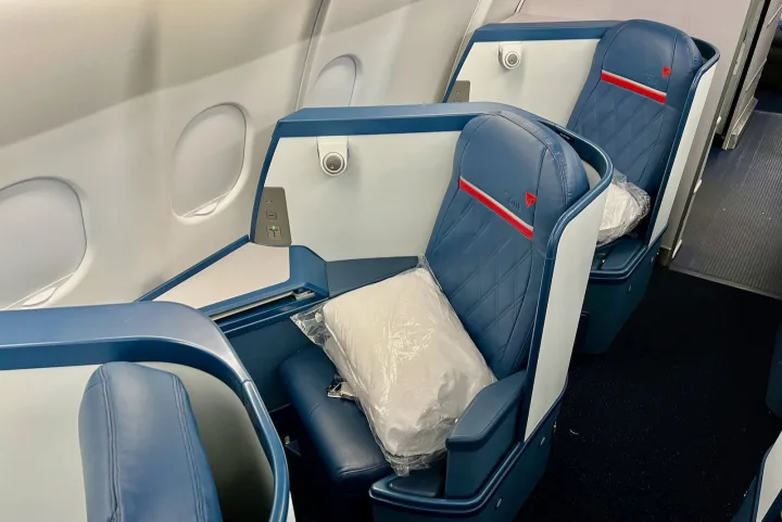 Delta business class seats in blue and white leather with amenity pillows, empty cabin.