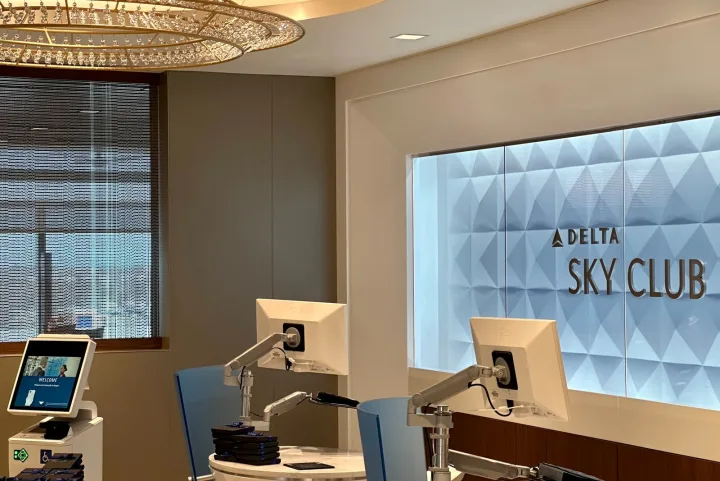 Delta Sky Club lounge entrance with illuminated logo sign and check-in kiosks.
