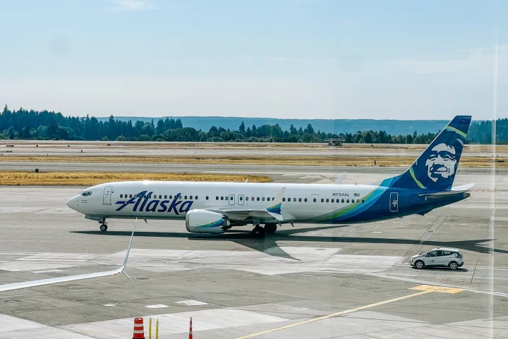 Alaska Airlines Boeing 737 aircraft on airport tarmac on a sunny day.