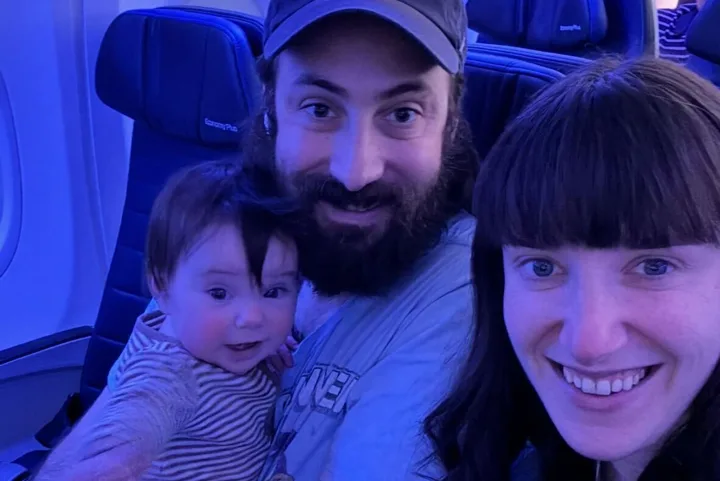 A man, woman, and baby taking a selfie together in United Airlines Economy Plus seats.