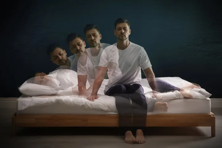 Multiple-exposure composite of a man rising from bed with eyes closed, depicting stages of movement.