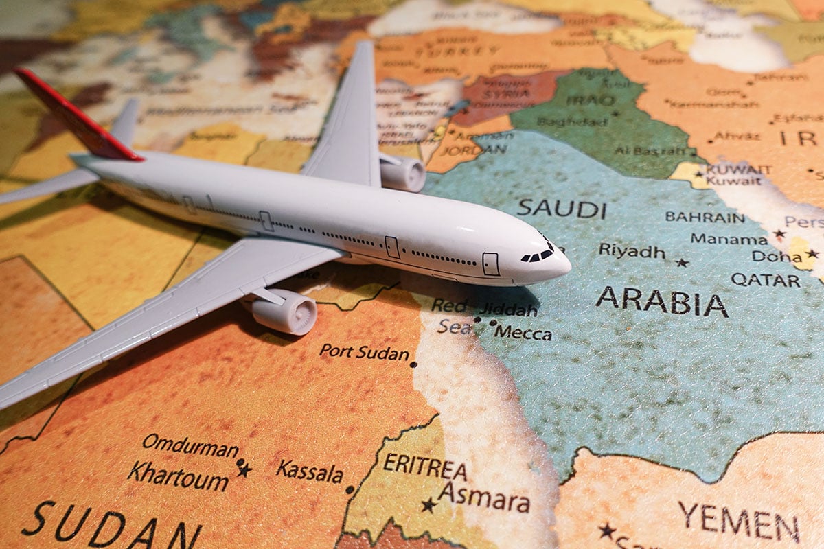 A toy airplane model placed on a colorful world map showing the Middle East region.
