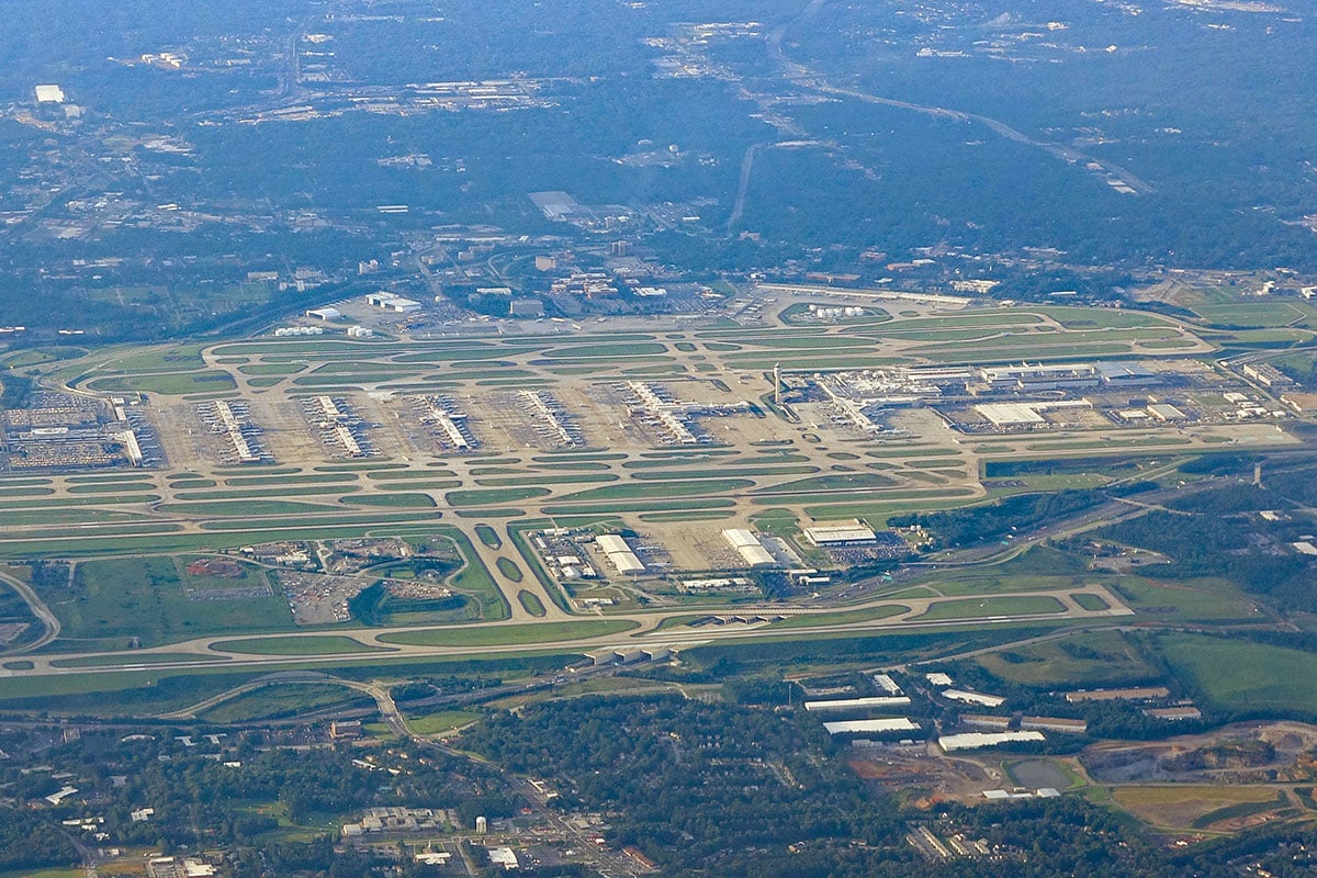 Aerial view of a large commercial airport with multiple runways and terminals surrounded by greenery.